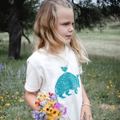 A girl holding flowers in an armadillo t-shirt.