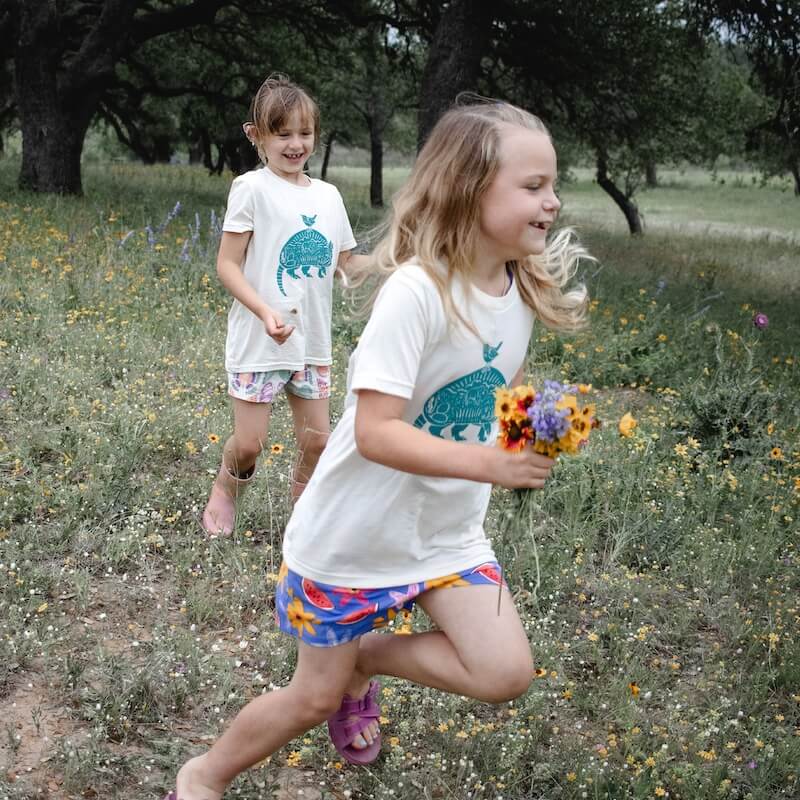 Two girls smiling and running in armadillo shirts.