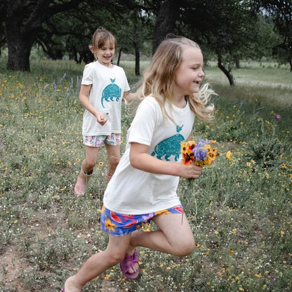 Two girls smiling and running in armadillo shirts.