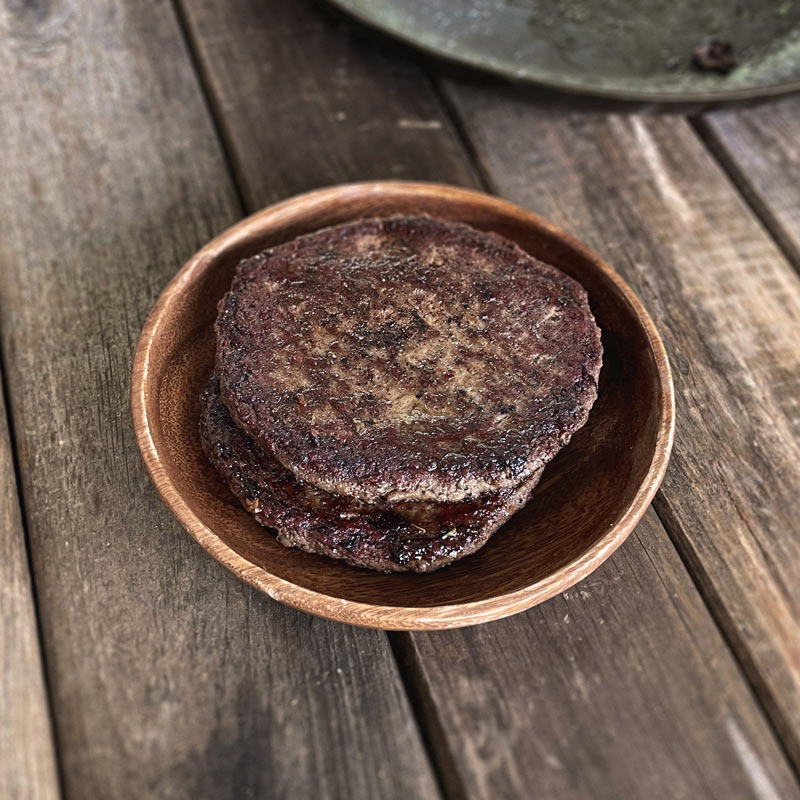 Freshly cooked burger patties stack on one another.