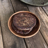 Freshly cooked burger patties stack on one another.