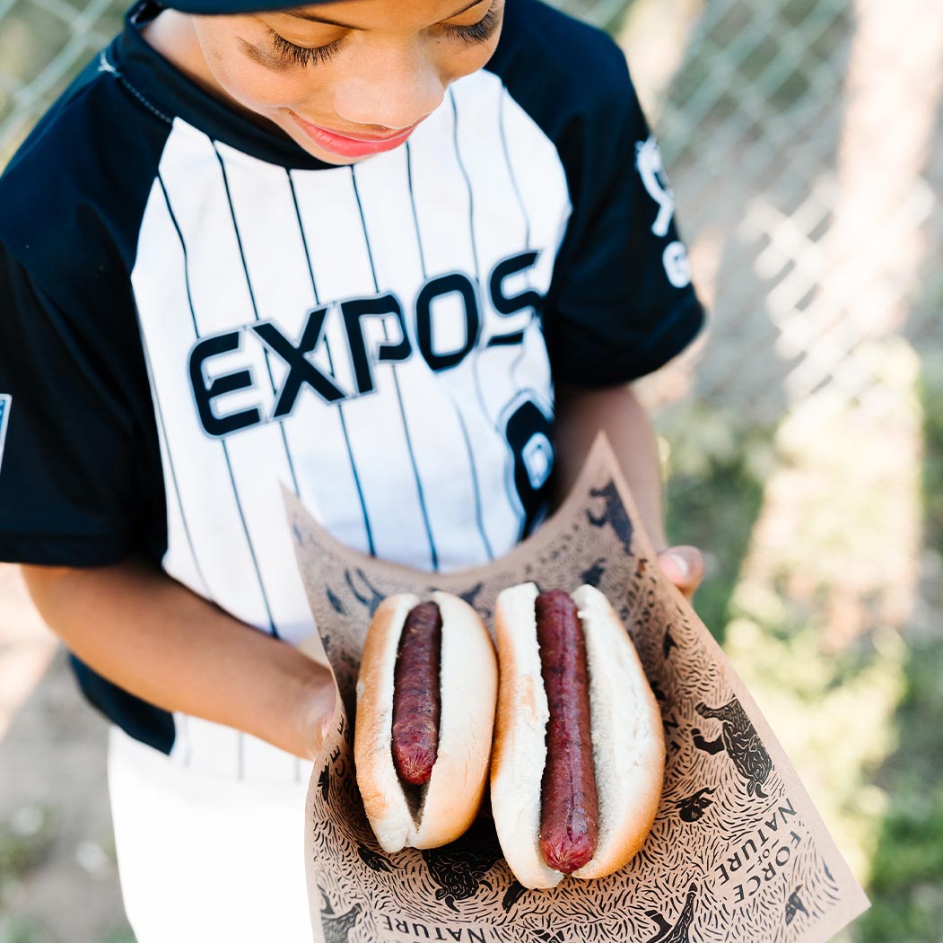 A child holding two hot dogs.