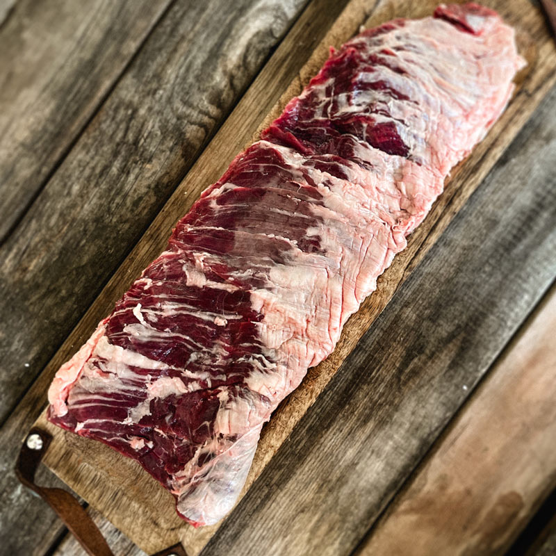 Raw skirt steak on a wooden cutting board.