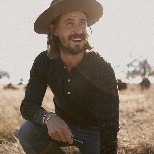 Photo of a kneeling and smiling in a large field