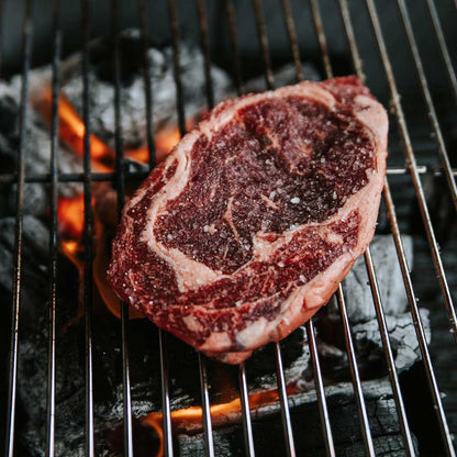 A steak cooking on a grill.