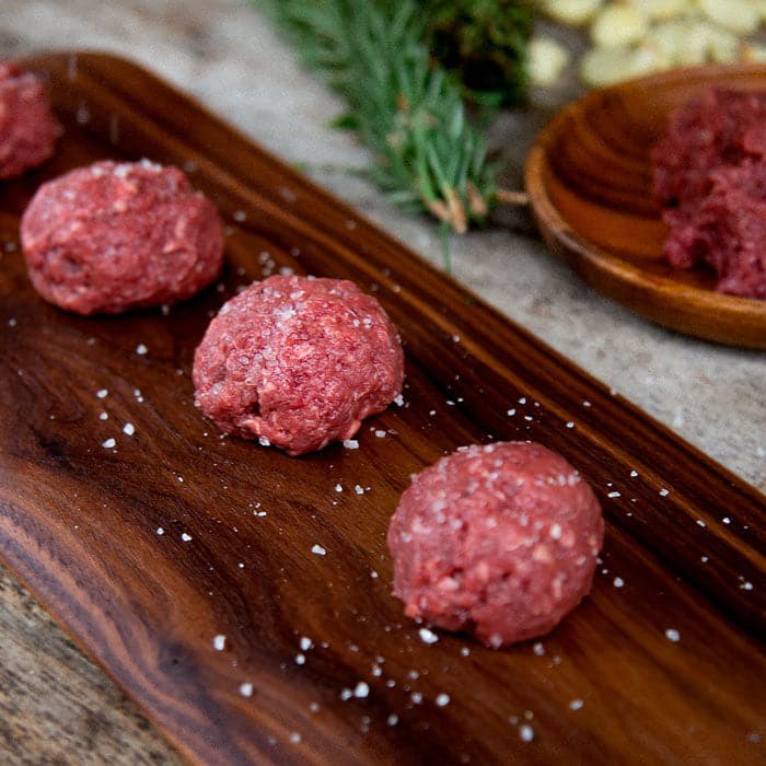 Raw meat freshly seasoned on a cutting board.