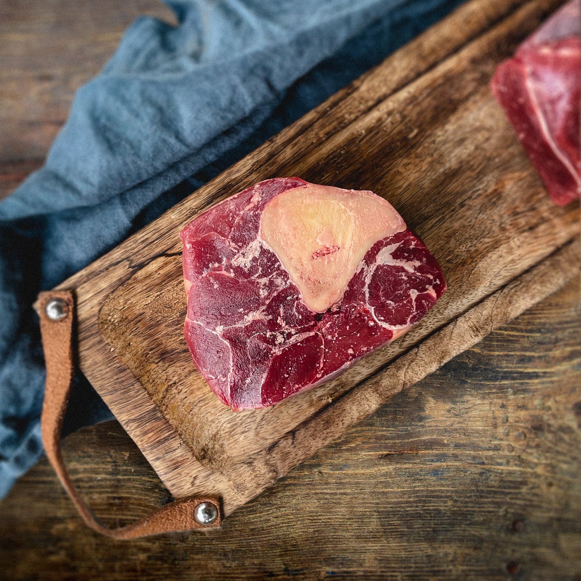 Bison Osso Buco raw on a cutting board.